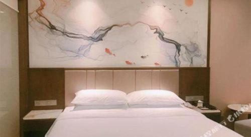 a bedroom with a bed with a painting above it at Venus Royal Hotel Nanning East High-Speed Railway Station in Nanning