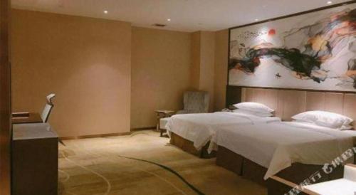 a bedroom with two beds and a painting on the wall at Venus Royal Hotel Nanning East High-Speed Railway Station in Nanning