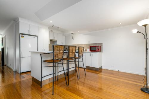 a kitchen with three bar stools and a counter at Spacious 2BR APT Panoramic Views Central Location - Hosted by CanStay in Narrabundah