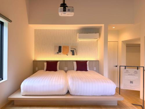 a bed with white sheets and red pillows in a room at Rakuten STAY Hakone Susuki Grass Fields in Sengokuhara