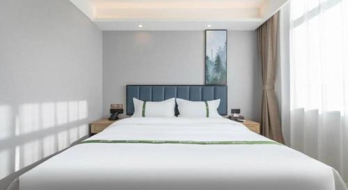 a bedroom with a large white bed and a window at GreenTree Inn Express Qingdao Jiaodong International Airport in Qingdao