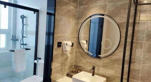 a bathroom with a shower and a sink and a mirror at GreenTree Inn Express Qingdao Jiaodong International Airport in Qingdao