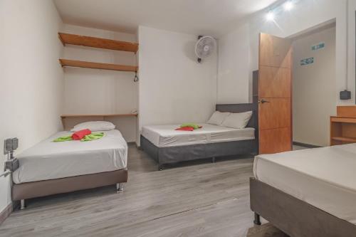 a room with two beds and a door to a bedroom at Hostal Machu Picchu Medellín in Estación El Salto