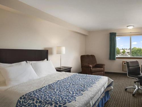 a hotel room with a bed and a chair and a window at Days Inn by Wyndham Lacey Olympia Area in Lacey