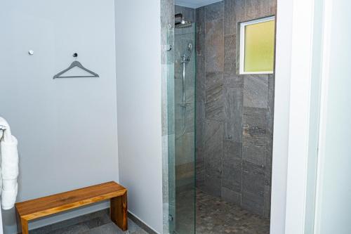 a bathroom with a shower with a wooden bench at Elan at Ballena Beach in Uvita