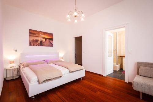 Habitación blanca con cama y lámpara de araña. en Operngasse Premium in "Your Vienna", en Viena