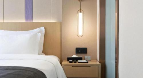 a hotel room with a bed and a night stand with a clock at Lavande Hotel Guangzhou Quzhuang Metro Station in Guangzhou