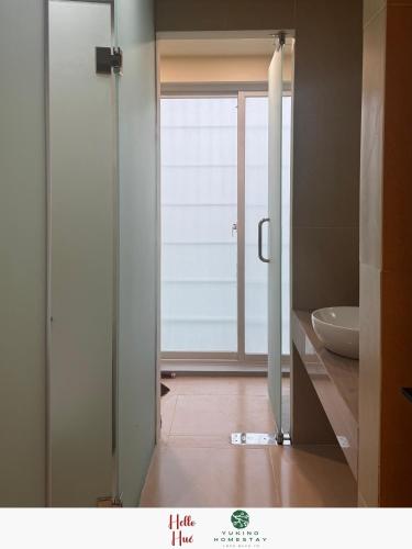 a bathroom with a door open to a bathroom with a sink at Yukino Homestay Vườn Ngôn Từ in Thôn Dương Xuân Hạ
