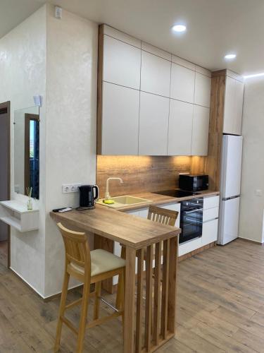 a kitchen with white cabinets and a wooden table and chairs at DOBA - LUKS клас 3-4 міс Завжди тепла ! in Mukacheve