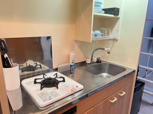 a kitchen counter with a stove and a sink at VESSEL Inn in Fukuoka
