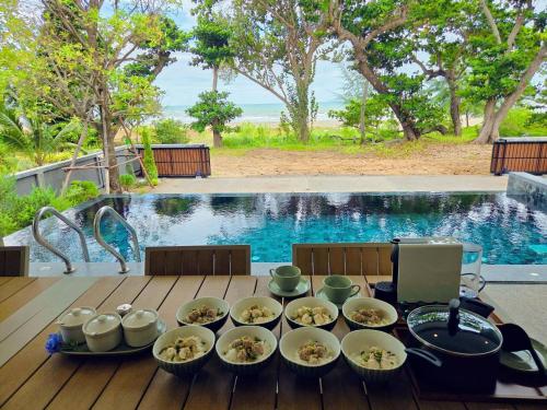 a table with bowls of food on it next to a pool at Merbrisa Rayong poolvilla-Ao khai beachfront in Mae Pim