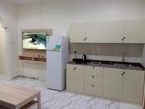 Una cocina con un refrigerador blanco y una mesa. en شقق ابراج الخير, en Abha