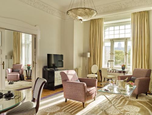 a living room with a couch and chairs and a tv at Four Seasons Hotel Gresham Palace Budapest in Budapest