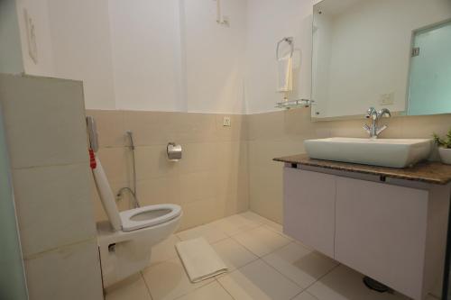 a bathroom with a toilet and a sink at Aliste Millennium Huda City Centre in Gurgaon