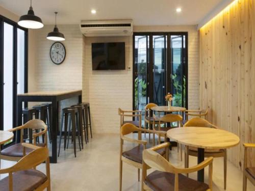 a restaurant with tables and chairs and a clock on the wall at Esy Hotel in Lamphun