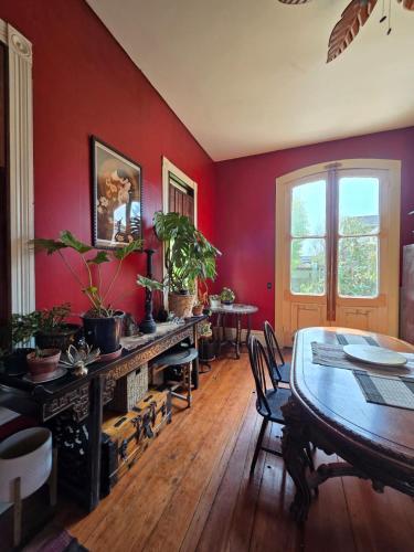 a dining room with red walls and a table with plants at Charming Unique Themed Victorian Elegance in Eureka
