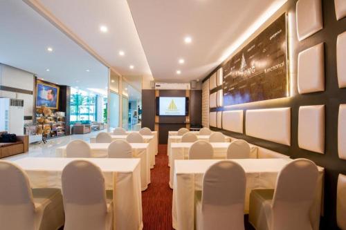 a conference room with white tables and chairs and a screen at Phuglong Hotel in Phayao