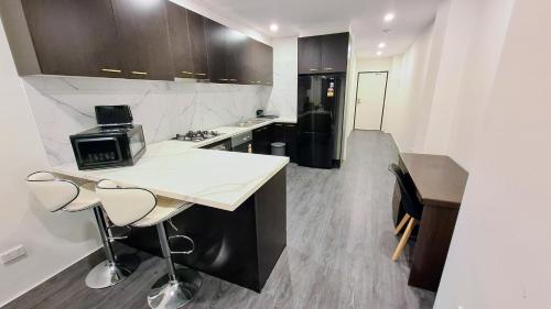 a kitchen with a white counter and a black refrigerator at Exodus Dandenong Apartment Hotel in Dandenong