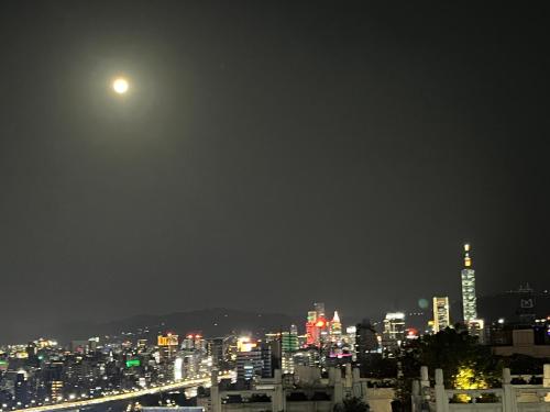 a view of a city at night with the moon at 樂居 台北 in T'ung-ko