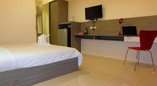 a hotel room with a bed and a desk with a tv at The Pride in Nakhon Pathom