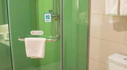 a bathroom with a glass shower with a towel at GreenTree Inn Qingdao Jiaozhou Jiaoping Road Express Hotel in Qingdao