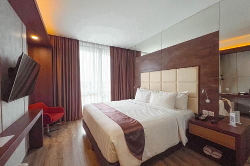 a hotel room with a bed and a television at Asialink Hotel Batam by Prasanthi in Nagoya