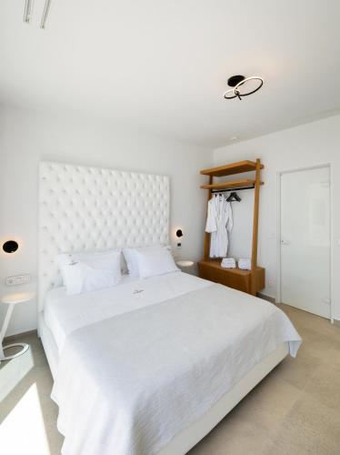 a white bedroom with a large bed with a white headboard at Aeliades Villas in Agios Nikitas