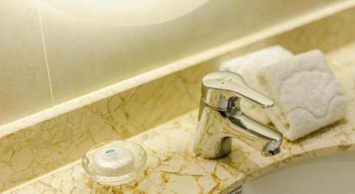 a bathroom sink with a faucet on a counter at Huachen Kenzo Hotel Hangzhou in Hangzhou