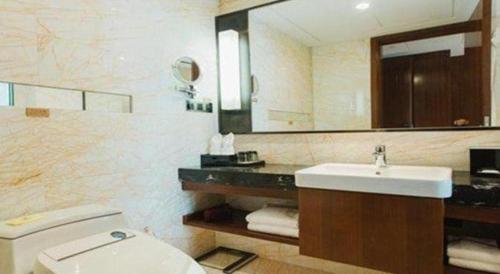 a bathroom with a sink and a toilet and a mirror at Grand Soluxe Zhongyou Hotel Shenzhen in Shenzhen