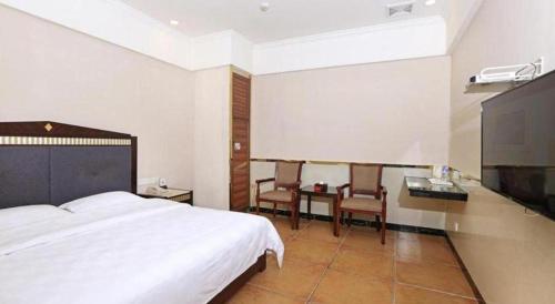a bedroom with a bed and a table and chairs at Zhongshan Hui Quan Hotel in Zhongshan