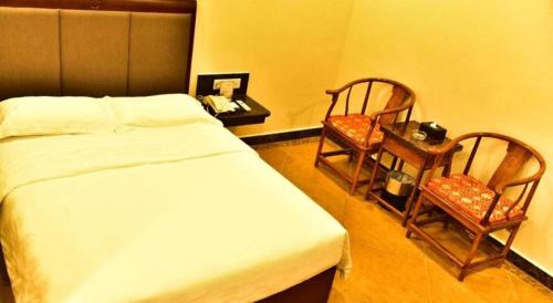 a bedroom with a bed and a table and two chairs at Zhongshan Hui Quan Hotel in Zhongshan