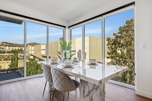 a dining room with a table and chairs and large windows at One Lux Stay - Hollywood in Los Angeles