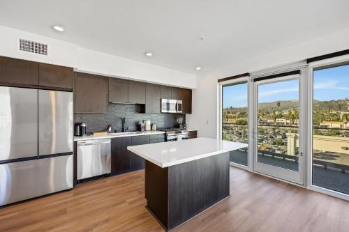a kitchen with stainless steel appliances and large windows at One Lux Stay - Hollywood in Los Angeles
