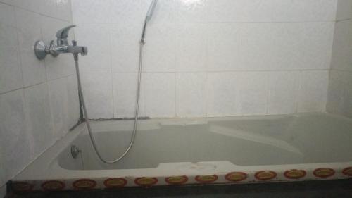 a bath tub with a shower in a bathroom at Raaha Luxury Home Stay in Mysore