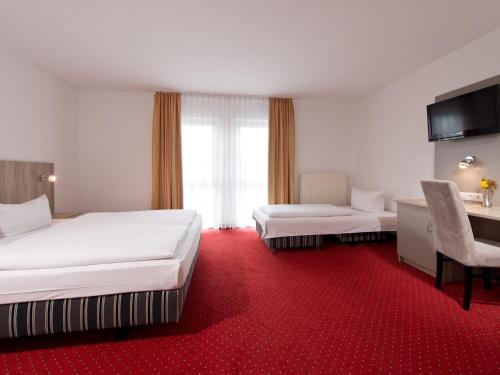 a hotel room with two beds and a desk and a chair at ACHAT Hotel Frankenthal in der Pfalz in Frankenthal