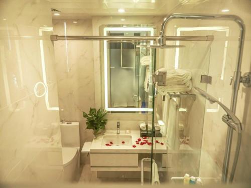 青島市にあるQingdao Galaxy Holiday Hotelの洗面台とシャワー付きの白いバスルーム