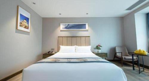 a bedroom with a large white bed and a desk at Landmark Hotel in Zhuhai