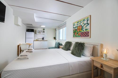 a bedroom with a white bed and a kitchen at Villa Ono at Bar Ilan University and Sheba Hospital in Qiryat Ono