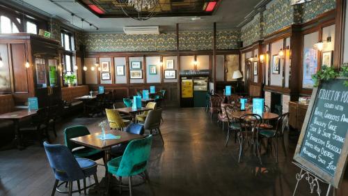 a restaurant with tables and chairs and a chalkboard at OYO The Kilburn Arms in London