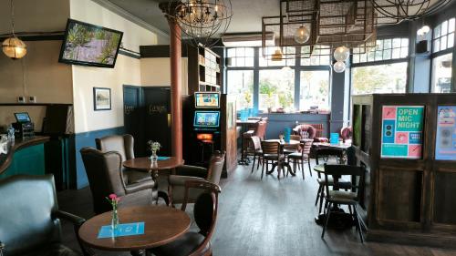 a restaurant with tables and chairs and a bar at OYO The Kilburn Arms in London
