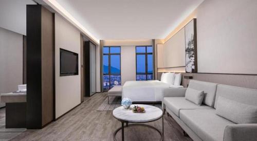 a hotel room with a couch and a bed and a living room at Wanda JIN Baise in Baise