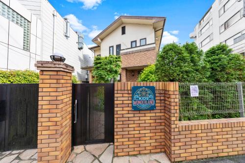 a sign on a brick fence in front of a house at 一棟貸しの親子で遊べる貸し切りアパート国立駅徒歩4分 in Kunitachi