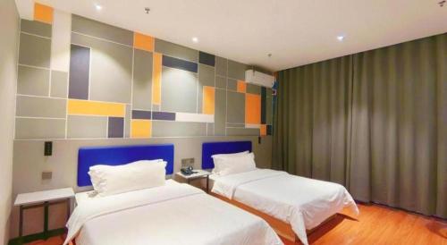 a bedroom with two beds and a colorful wall at 7 Days Inn Yining Xintiandi in Kipekyüzi