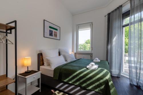 a bedroom with a bed with a green blanket and a window at Zentral gelegenes 3 BR Work&Soul Apartment, ideal zum Entspannen und Arbeiten in Neustadt an der Weinstraße