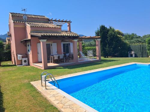 a villa with a swimming pool in front of a house at Villa Filia in Almiros Beach