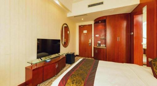 a bedroom with a bed and a flat screen tv at Junyu Grand Hotel Qinhuangdao in Qinhuangdao
