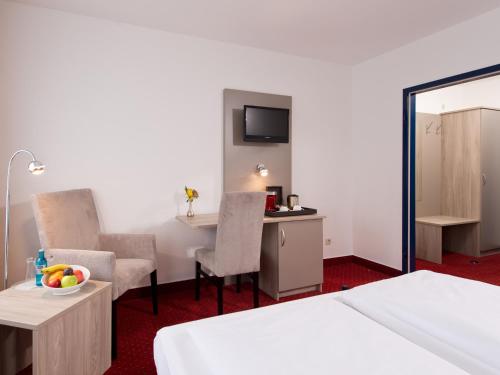 a hotel room with a bed and a table and chairs at ACHAT Hotel Frankenthal in der Pfalz in Frankenthal