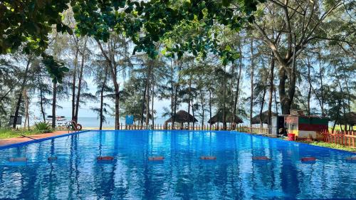 une grande piscine bleue avec des arbres en arrière-plan dans l'établissement The Beach House Ho Tram Resort, 