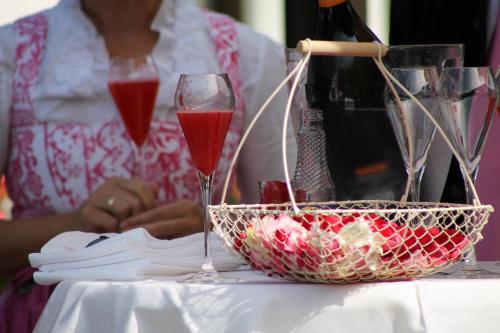 a woman sitting at a table with two glasses of wine at Hotel Seefischer - Finest Hideaway in Döbriach