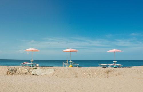 a group of umbrellas on a beach with the ocean at Villino Bavassano - Dimora Storica in Rimini